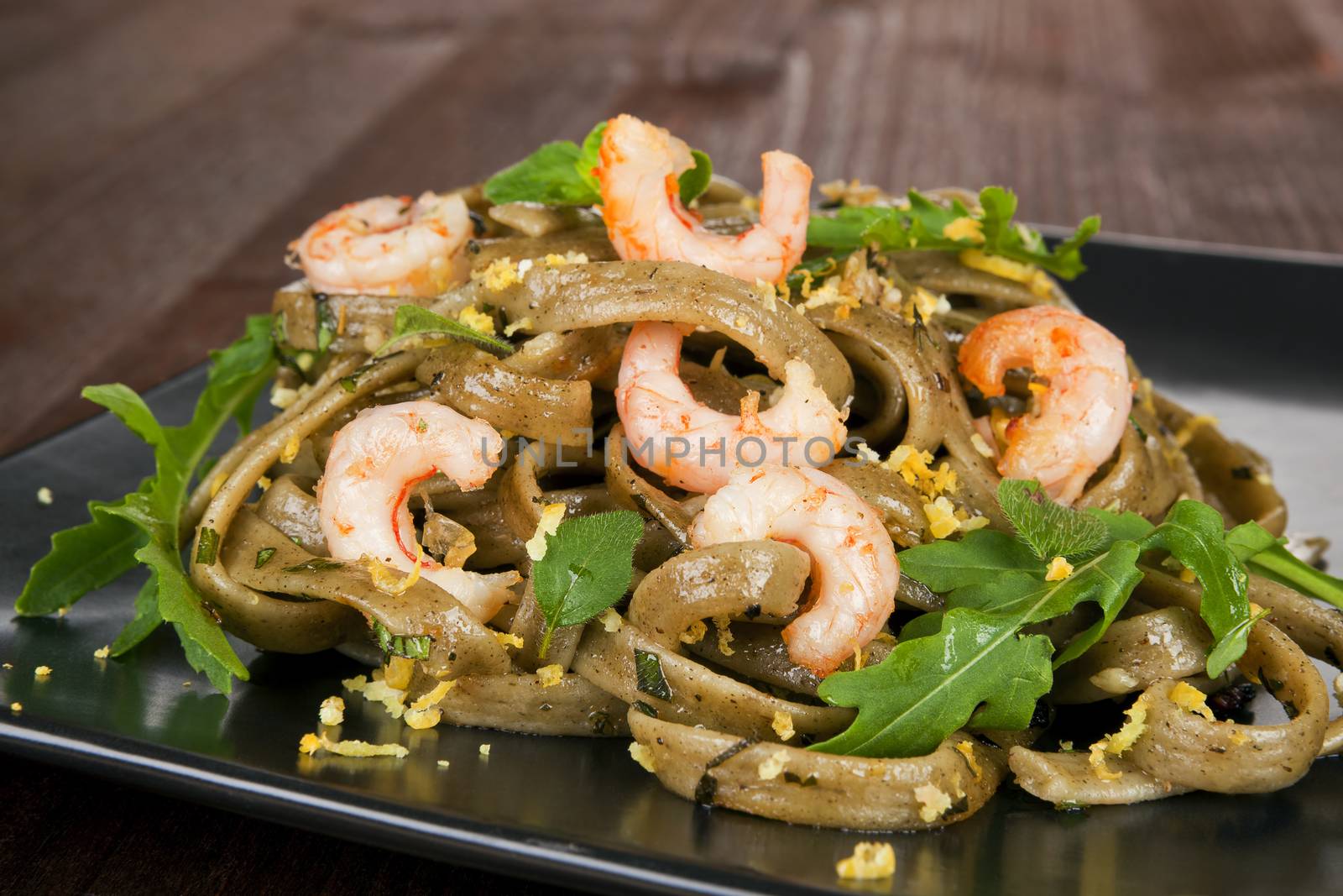 Luxurious seafood pasta on black plate with fresh arugula.