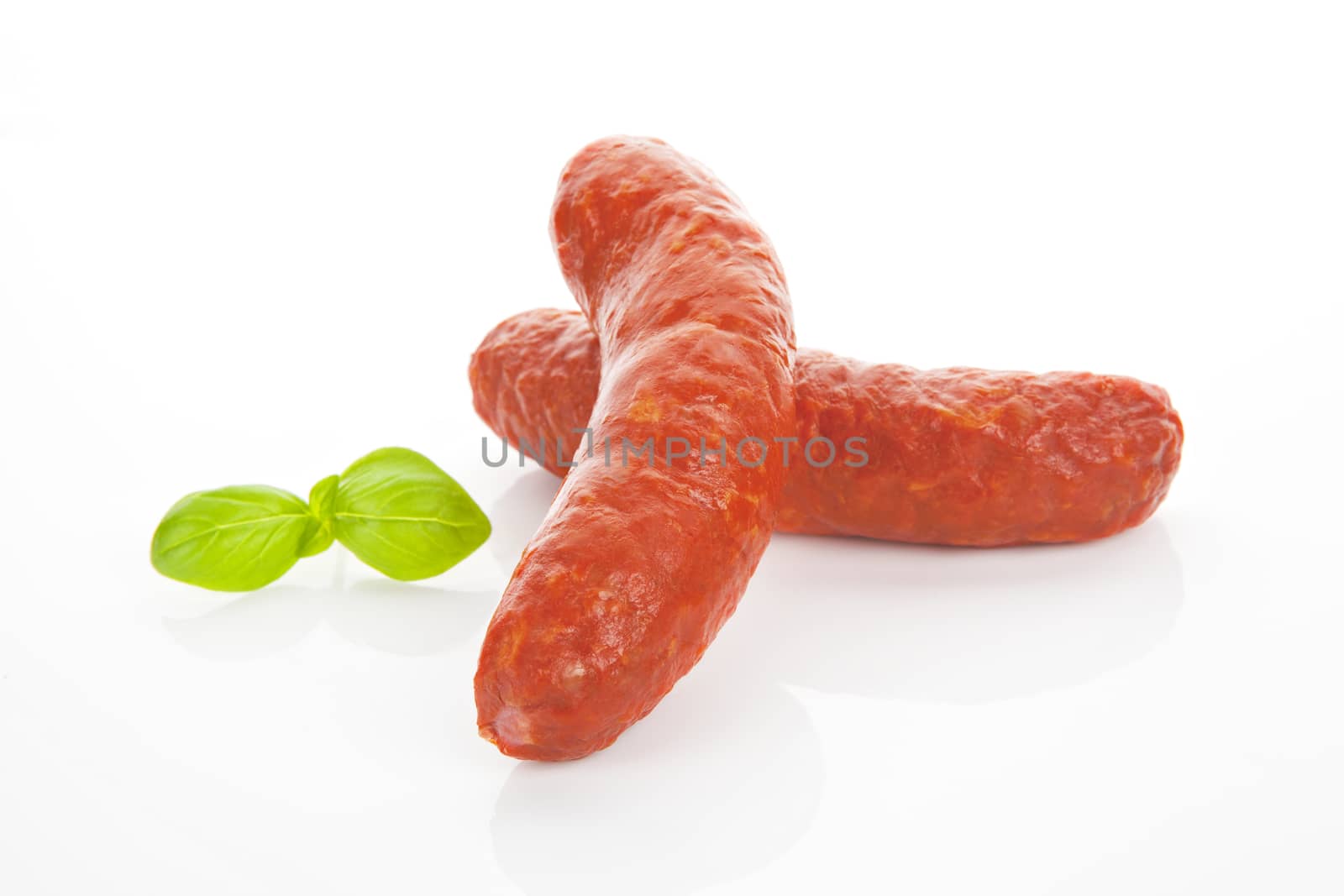 Two red sausages isolated on white background with fresh basil.