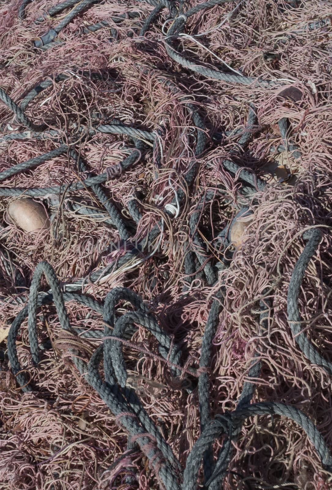 Black and brown fishing nets and ropes tangled together full frame.