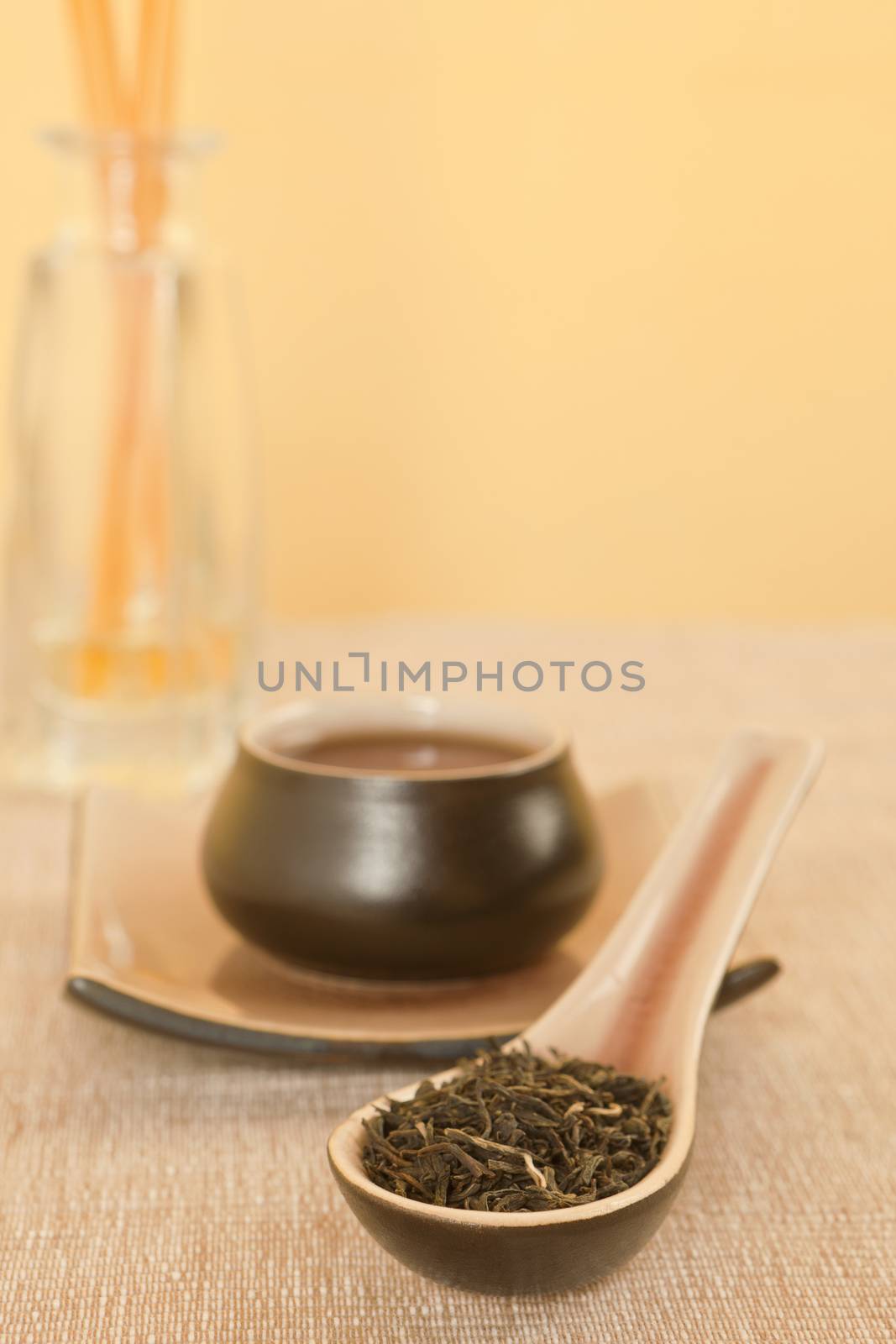 Black tea leaves on spoon, tea in tea bowl in background.