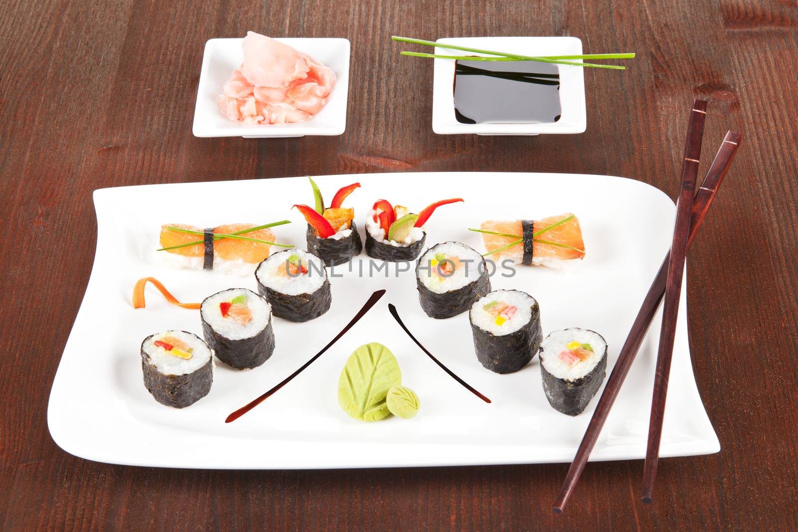 Sushi plate with maki sushi, nigiri sushi, wasabi and chopsticks. Soy sauce and ginger in white bowl.