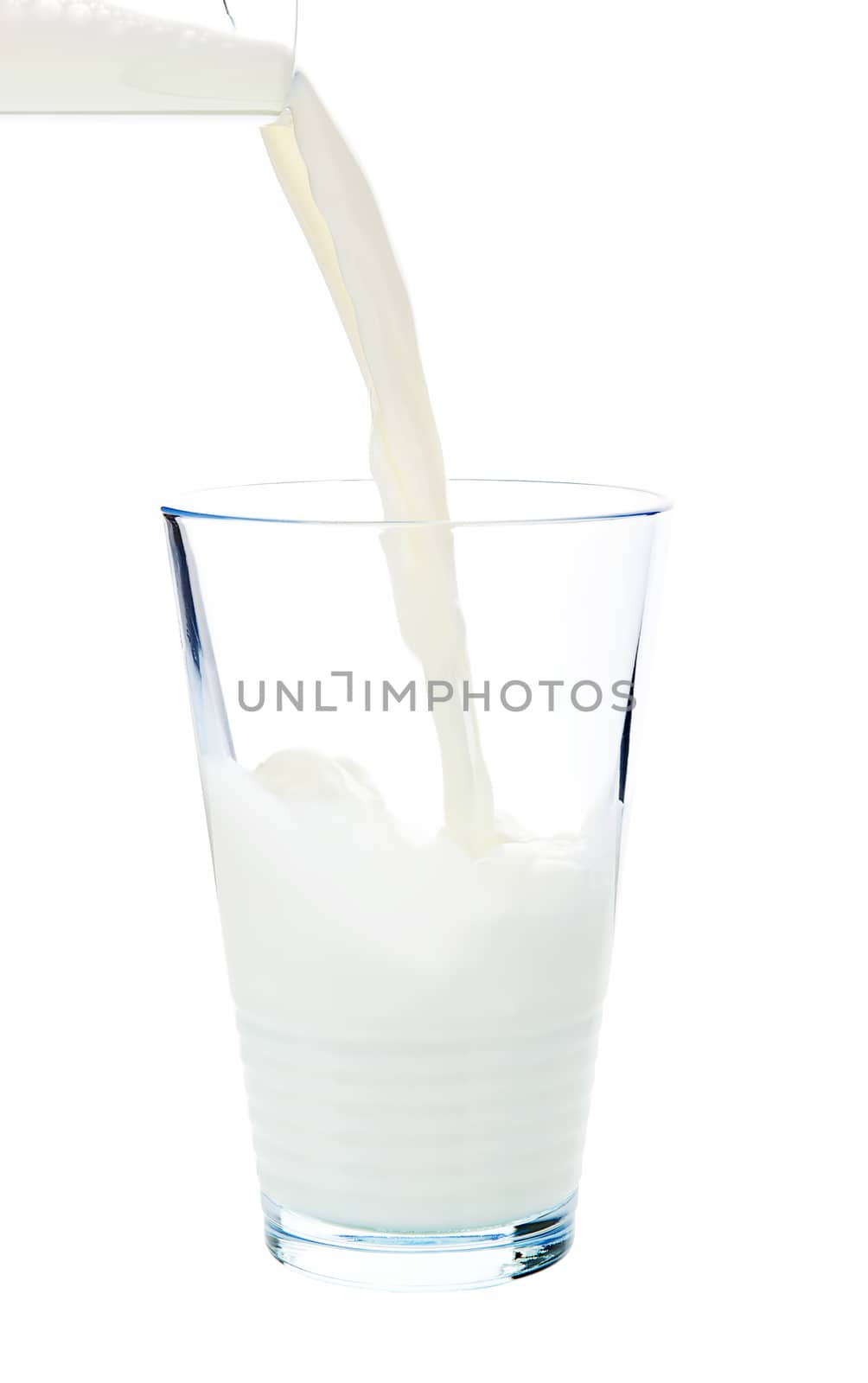 Pouring milk into a glass isolated on white background with clipping path.