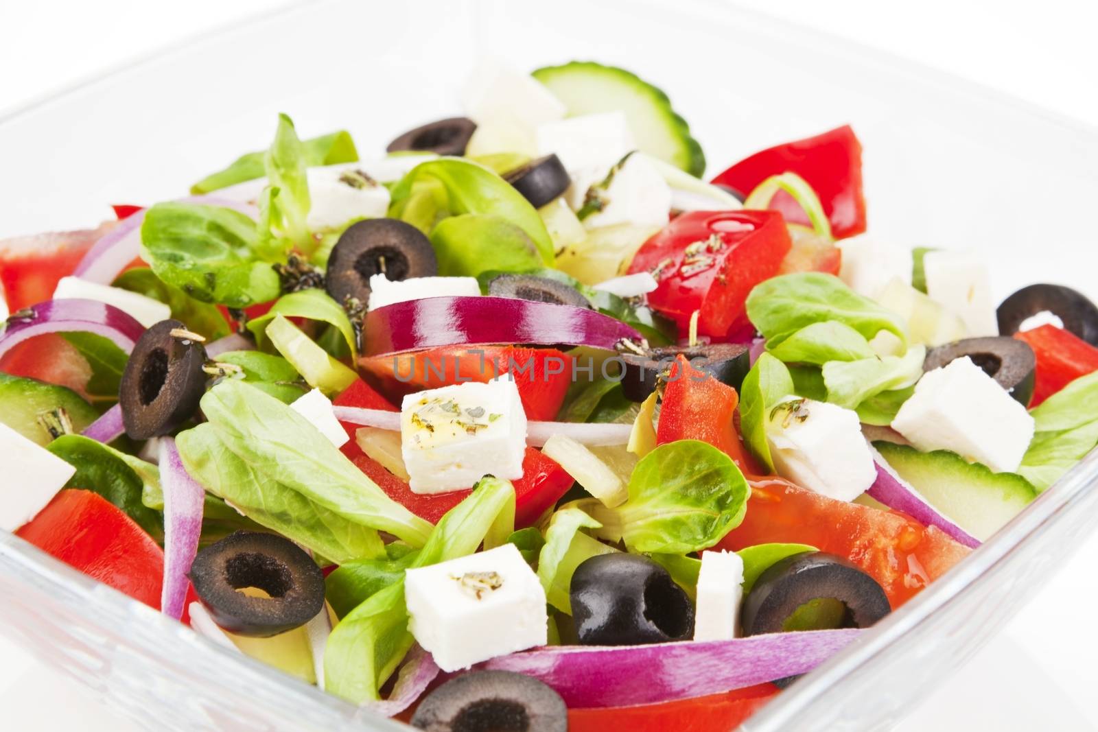 Fresh salad in glass bowl. Onion, olive, tomato, cucumber and goat cheese salad.