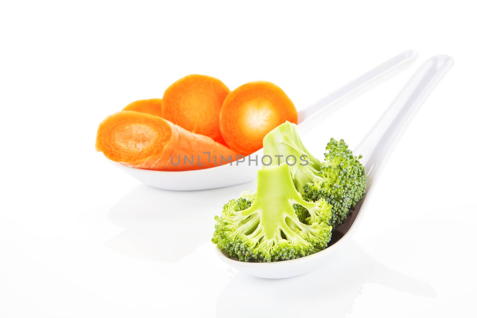 Broccoli and carrot pieces on white spoon isolated on white background.