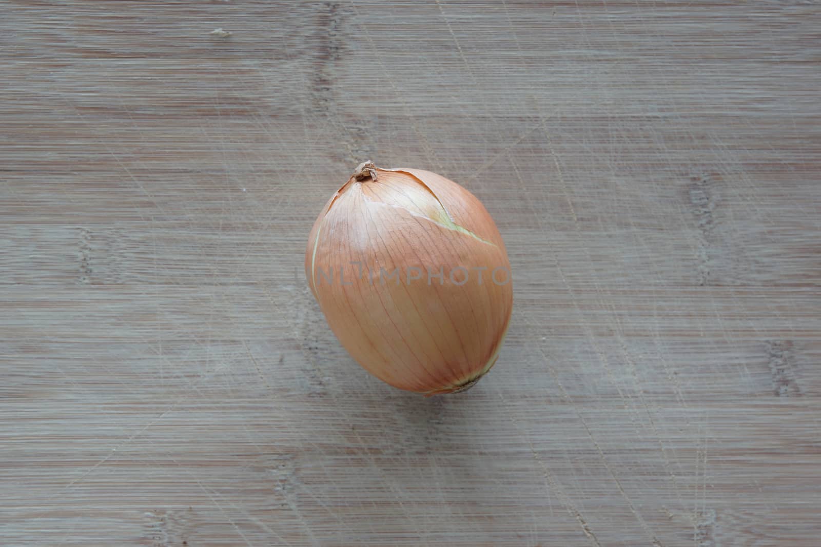 A solo white onion on top of a cutting board