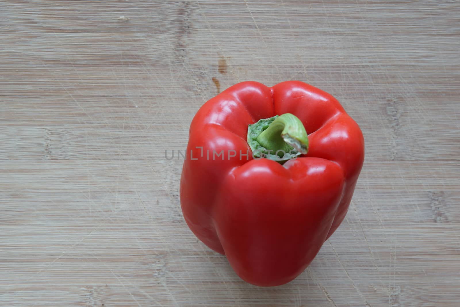 A solo red pepper standing on a cutting board