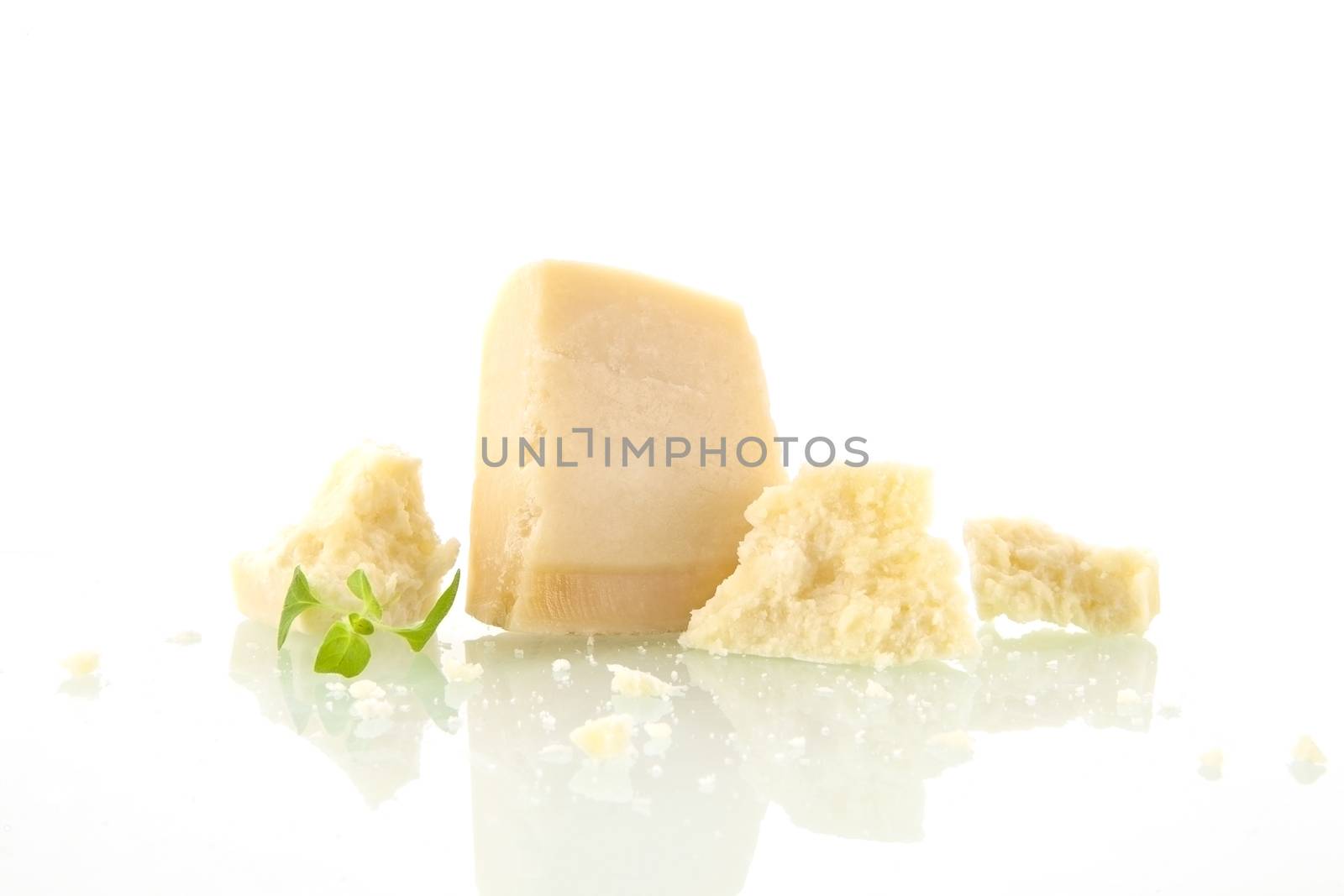 Parmesan pieces isolated on white background with basil leaves. Cheese background.