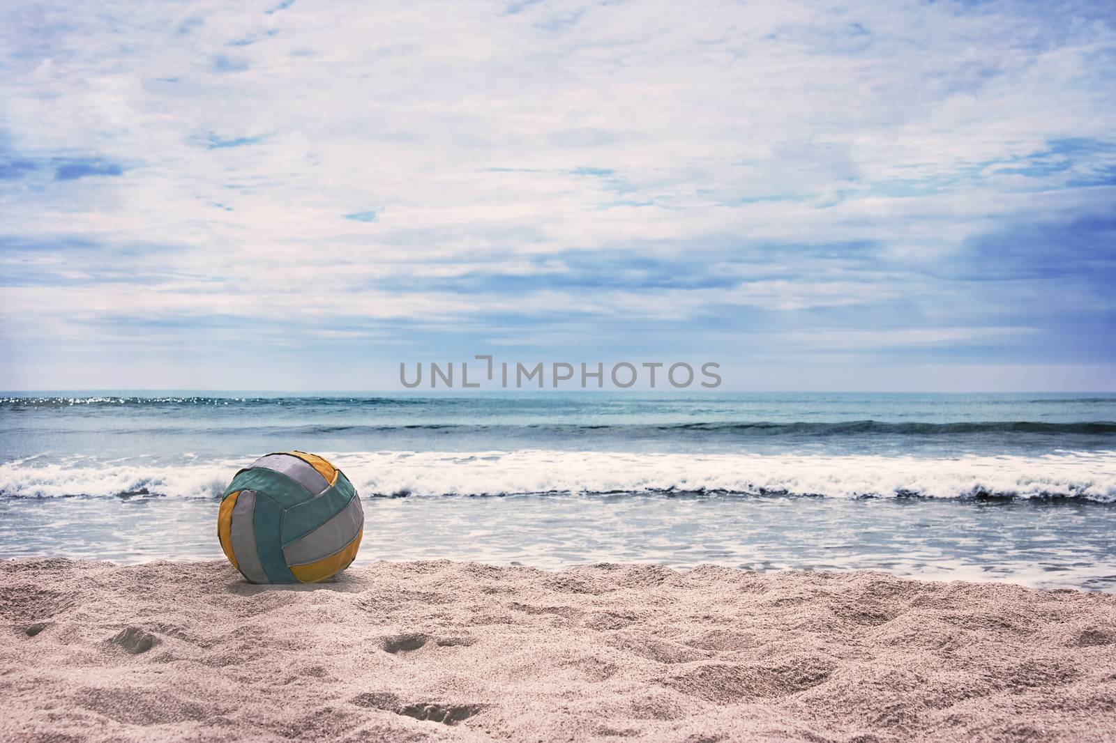 Volleyball ball on empty beach against blue sky and turquoise ocean. Summer.