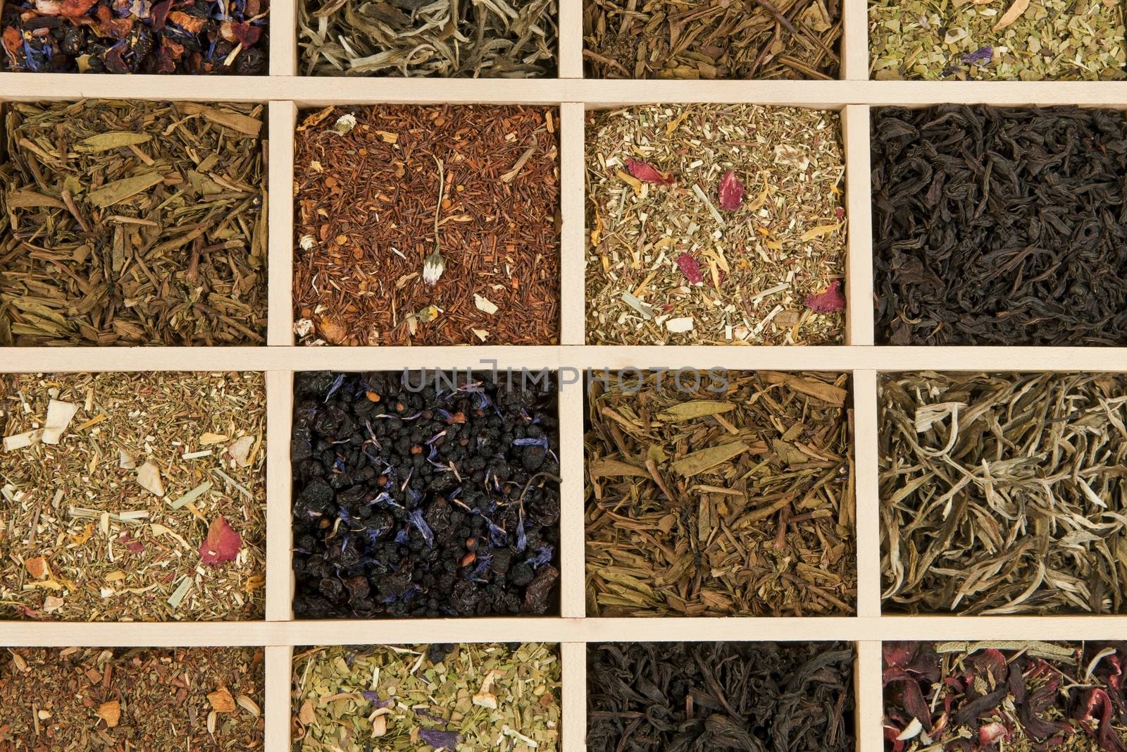 Various dry tea leaves - green, black, rooibos in wooden box.