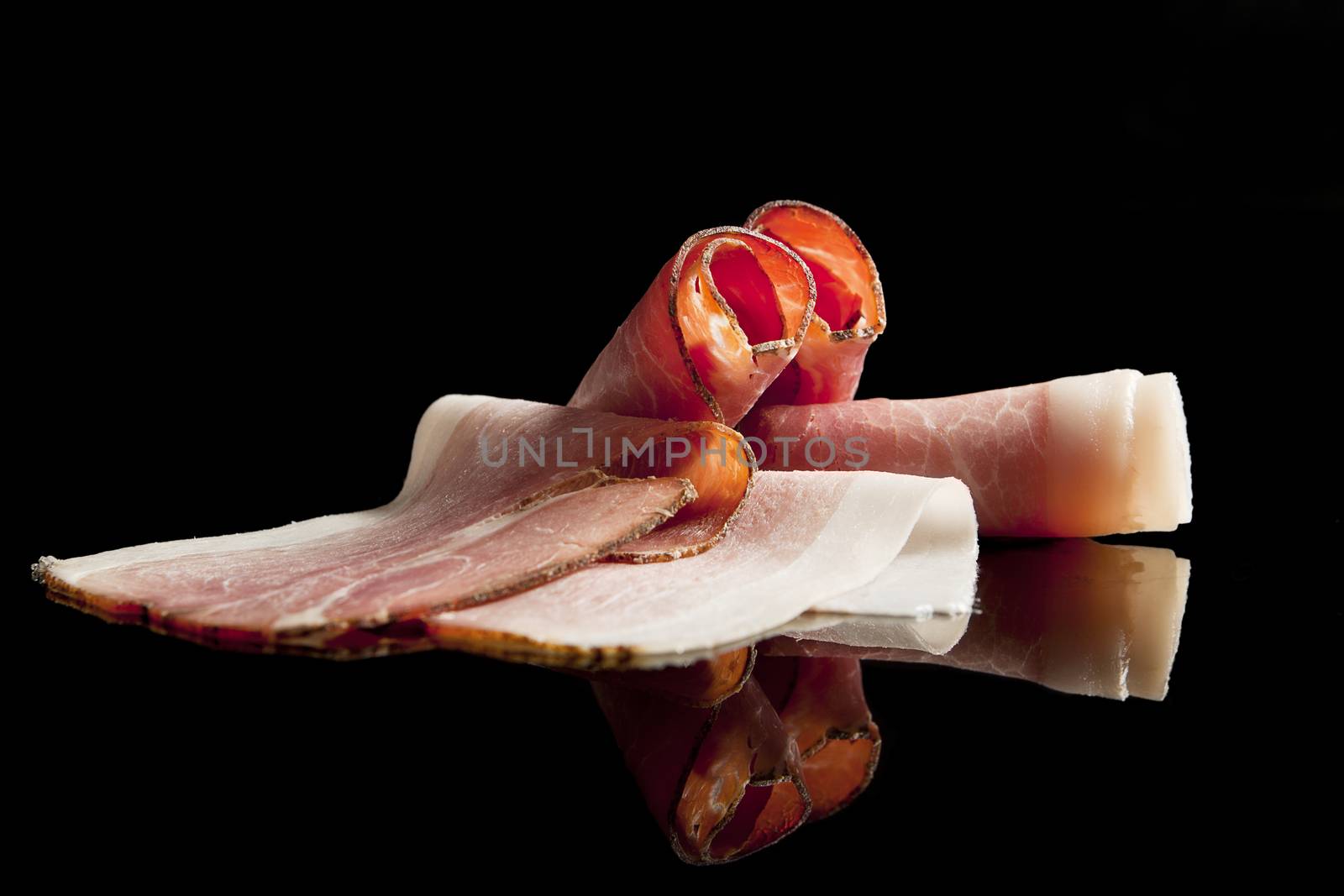 Bacon and ham slices isolated on black background.