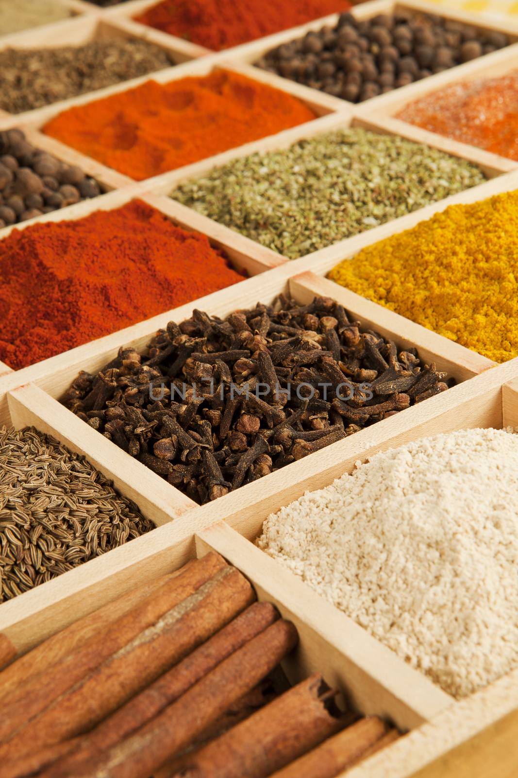 Wooden box with different herbs and spices - pepper, paprika, cumin and others.