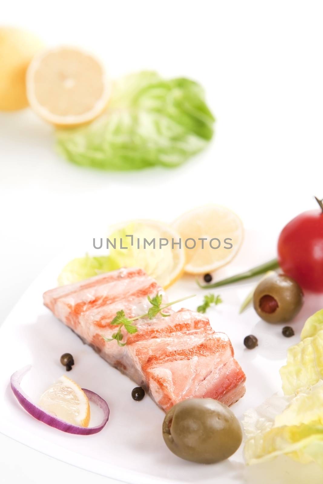Grilled salmon steak piece with olives, salad, onion and lemon.