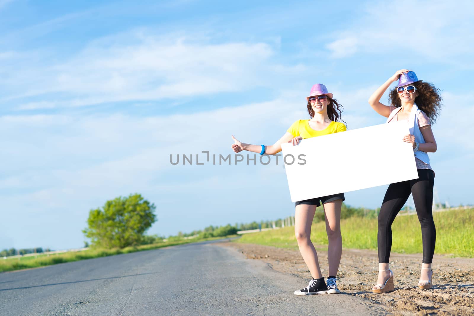 Two young women stand with a blank banner by adam121