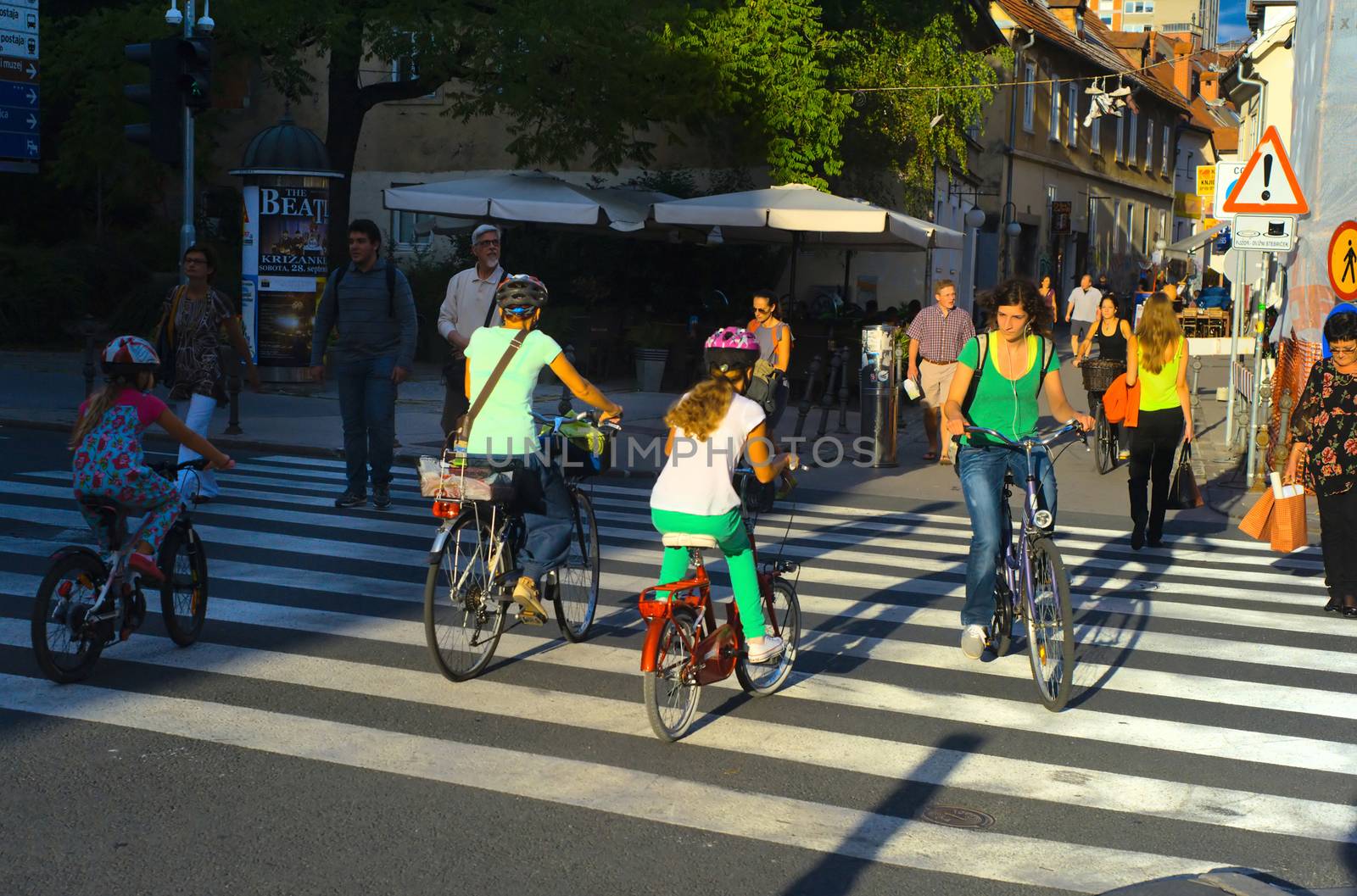 LUJBLJANA, SLOVENIA - SEPTEMBER 9, 2013: Unidentified people crossing street and riding bicycles on the street of Ljubljana. The downtown quarter usually attracts lots of tourists.