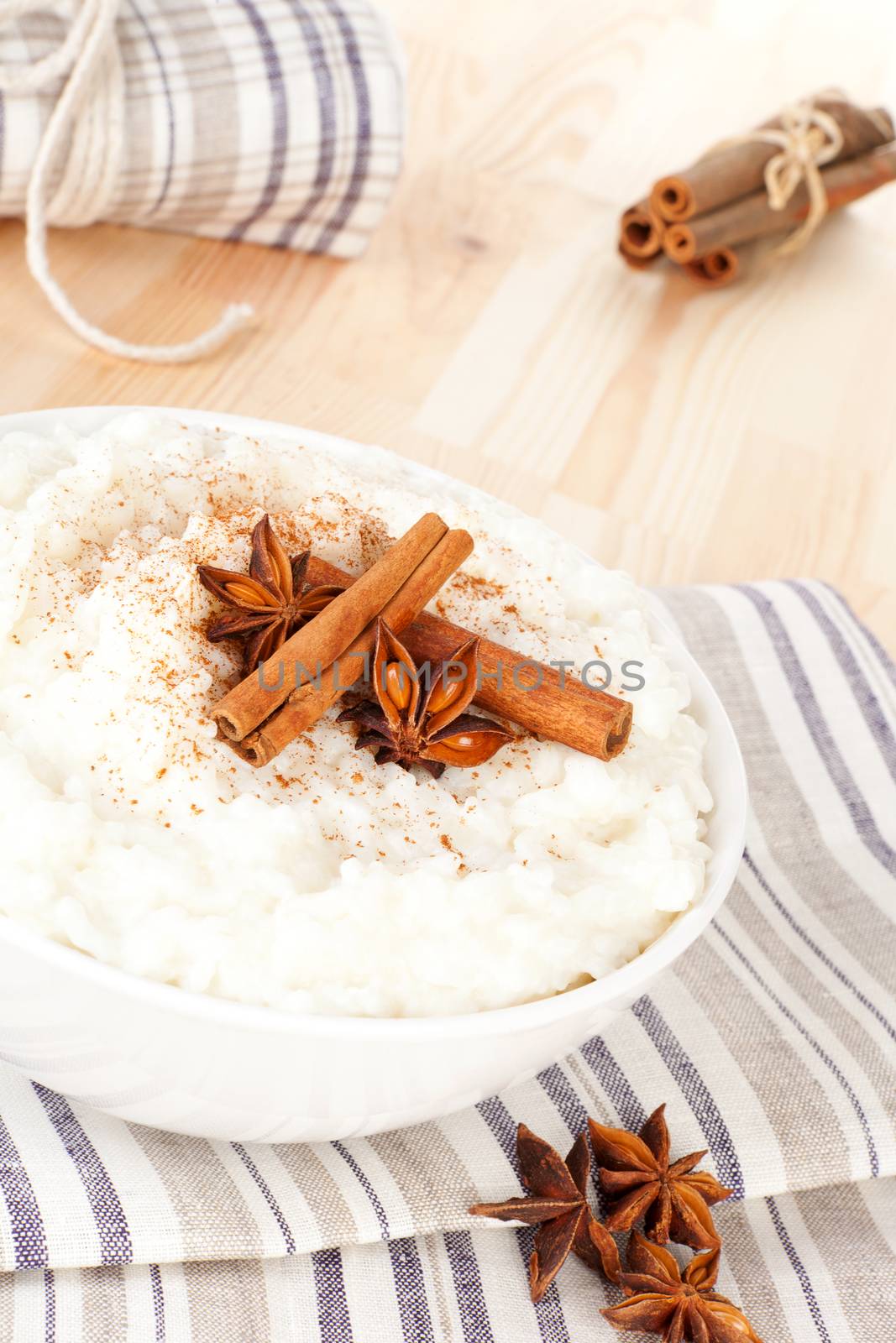 Culinary rice pudding with cinnamon and star anise garnish in white bowl. Delicious vegetarian food.