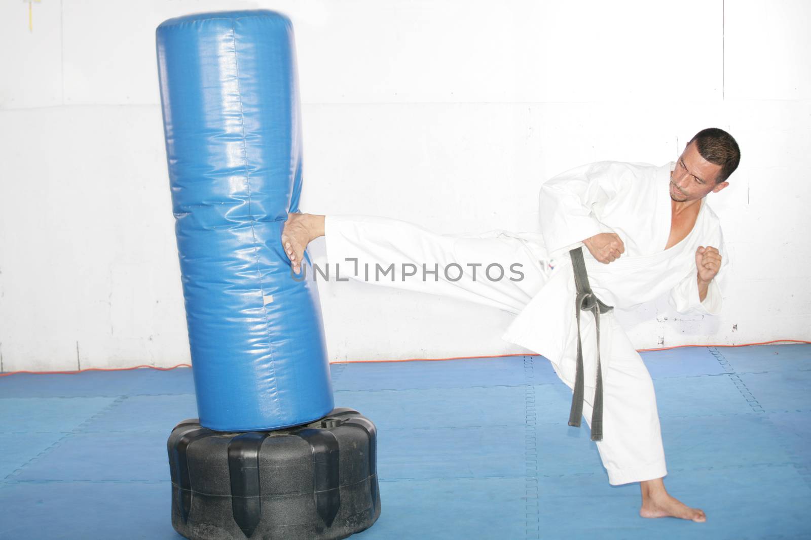 Black belt Karate man practicing in a sandbag