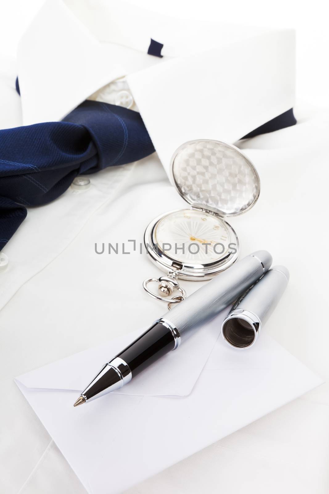 Elegant business still life with white dress shirt, blue tie, pen, envelope and silver pocket watch. Business concept.