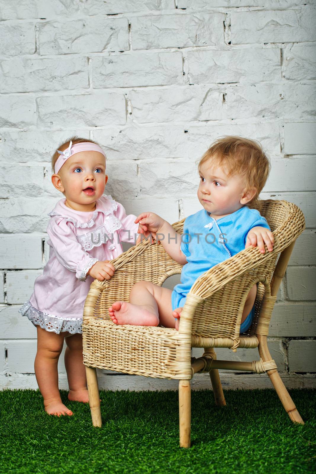 Brother and sister playing in the backyard next to the wicker chair