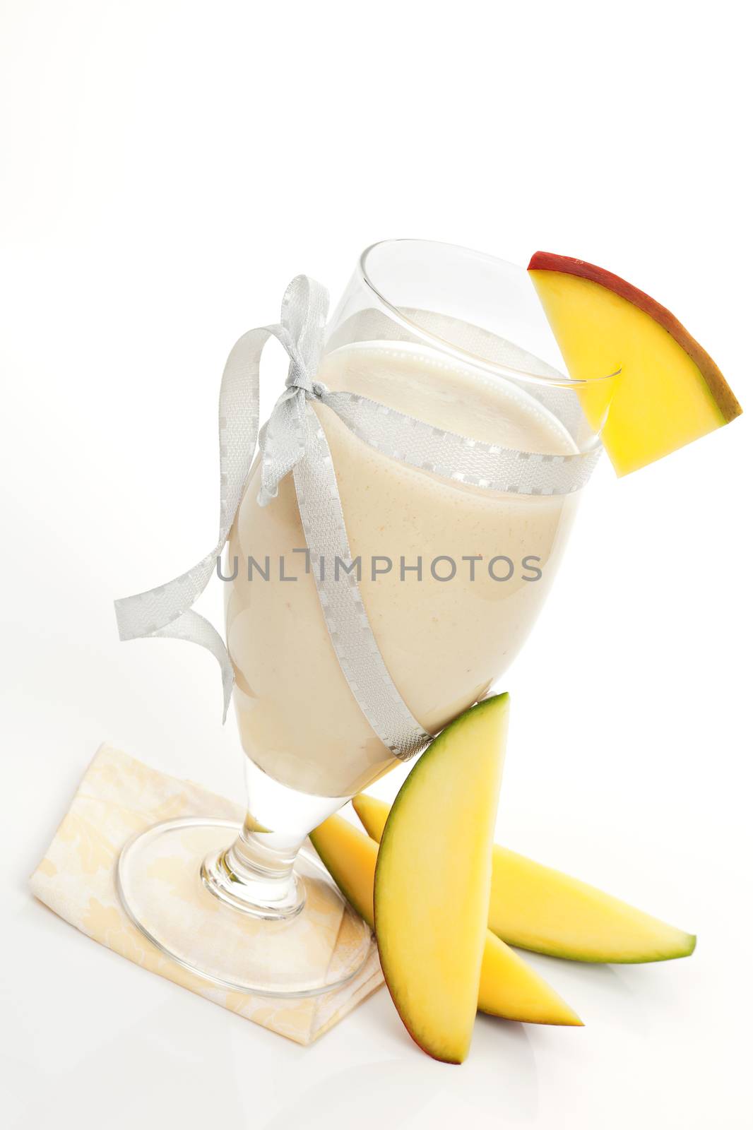 Tropical cocktail. Mango lassie in glass with fresh mango pieces isolated on white background. Summer drinks.