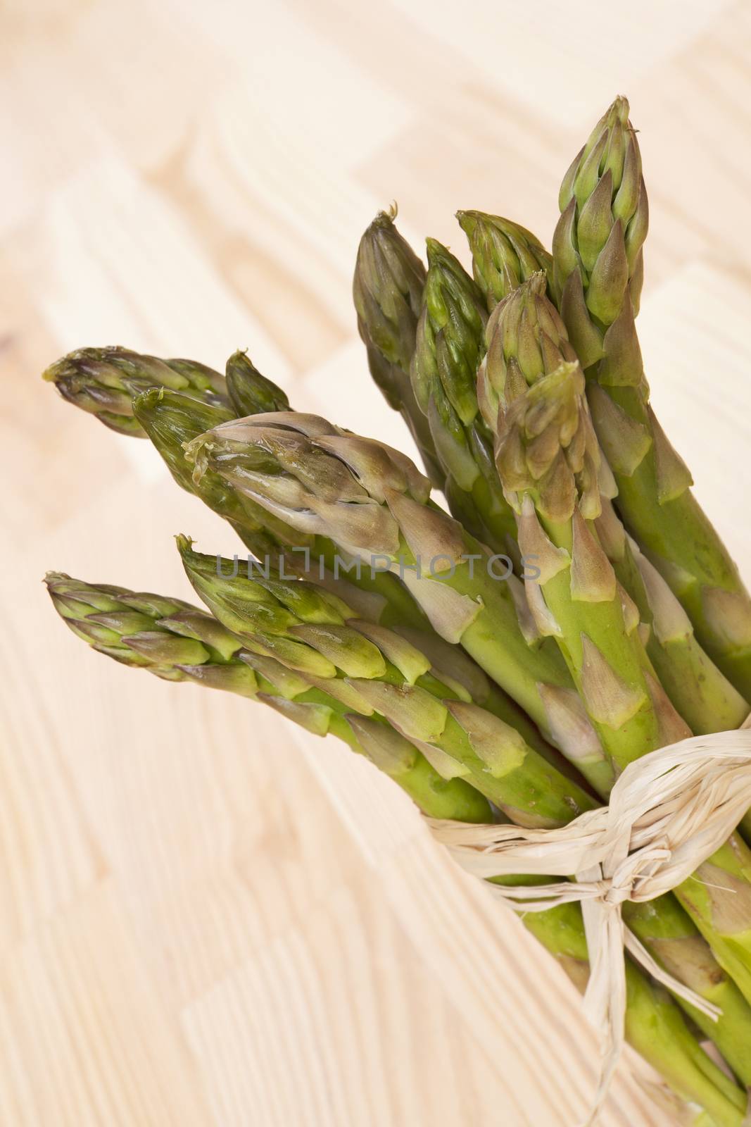 Fresh delicious asparagus bundle on wooden background. Fresh healthy summer vegetable.