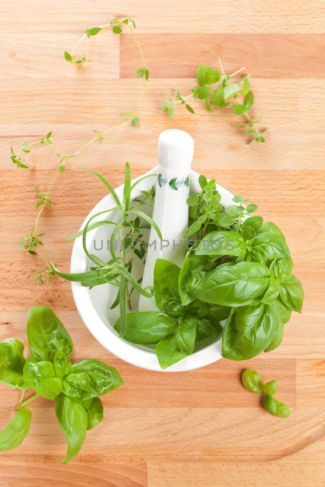 Fresh culinary aromatic herbs basil, thyme and rosemary in mortar with pestle on wooden background. Top view.
