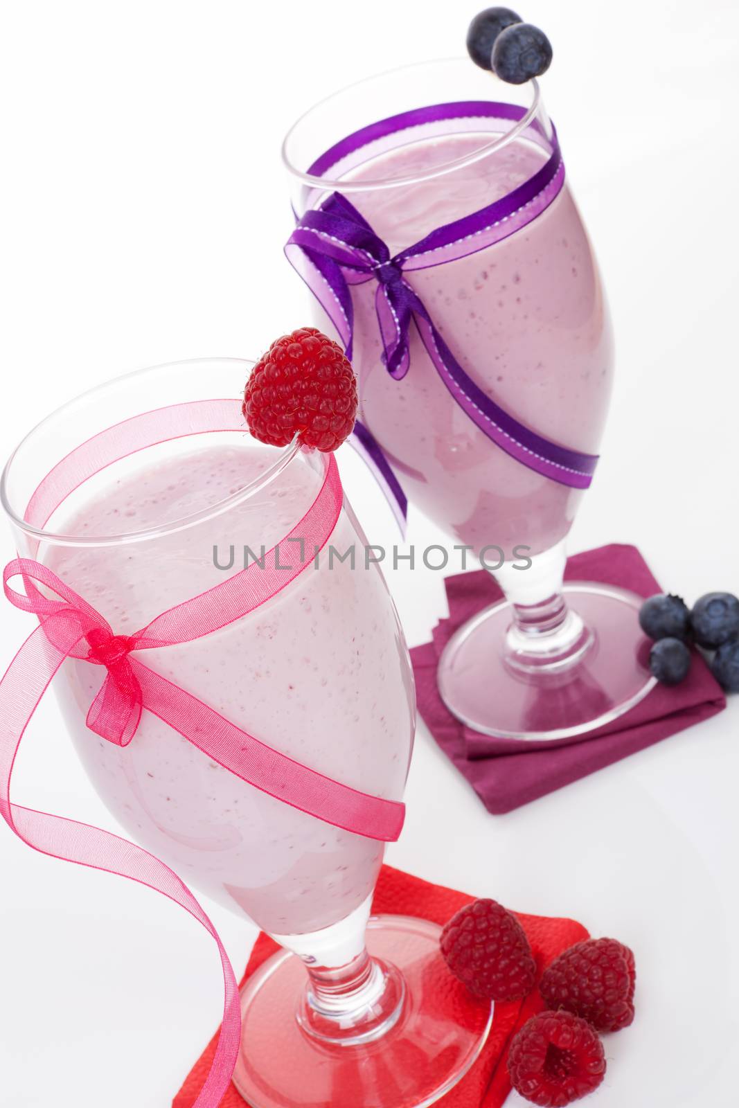 Raspberry and blueberry smoothie with fresh fruits in cocktail glass isolated on white background. Fresh summer drinks.