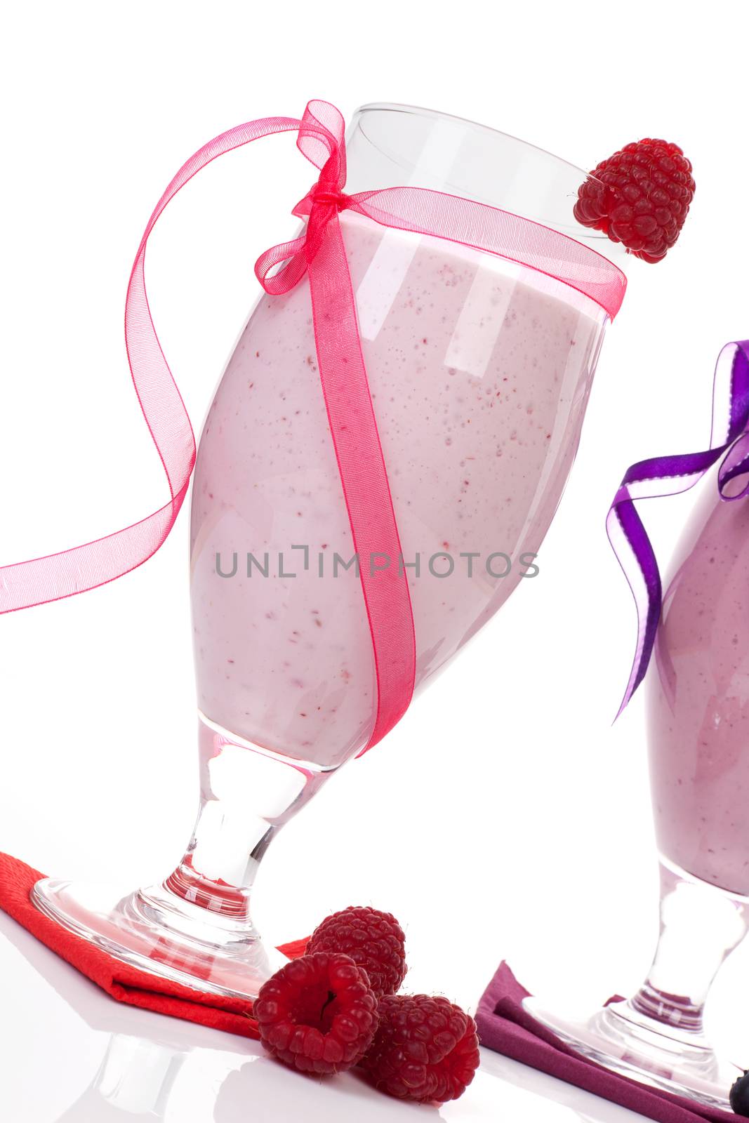 Raspberry yogurt shake with fresh raspberries decorated with pink ribbon isolated on white background. Luxurious summer drinks.