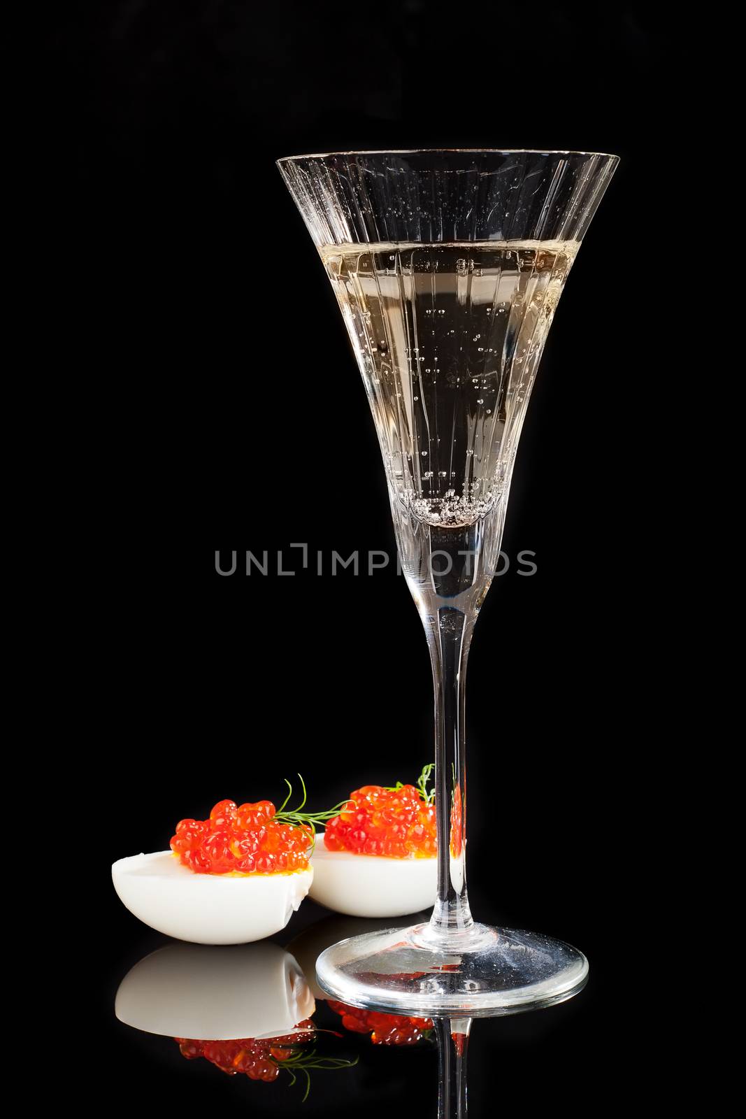 Caviar in egg with dill and champagne in glass isolated on black background. Luxury concept. 