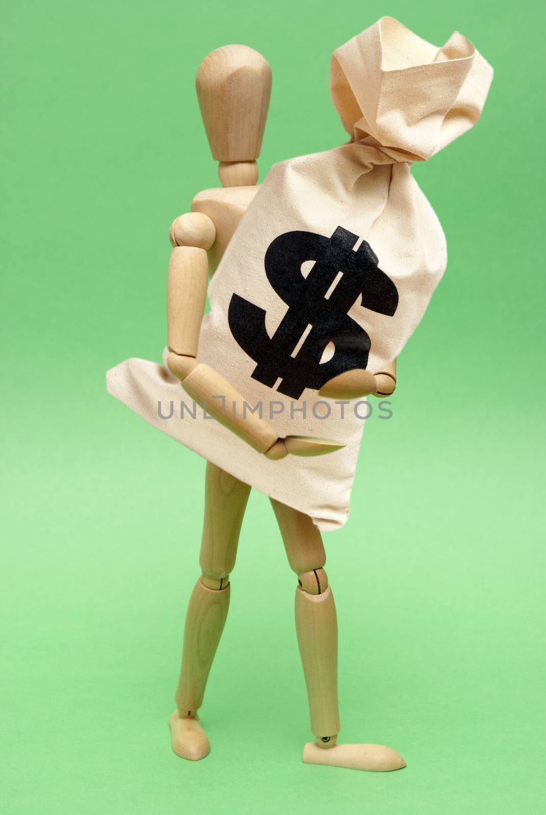 A wooden guy holds onto a large bag of money for many financial concepts.