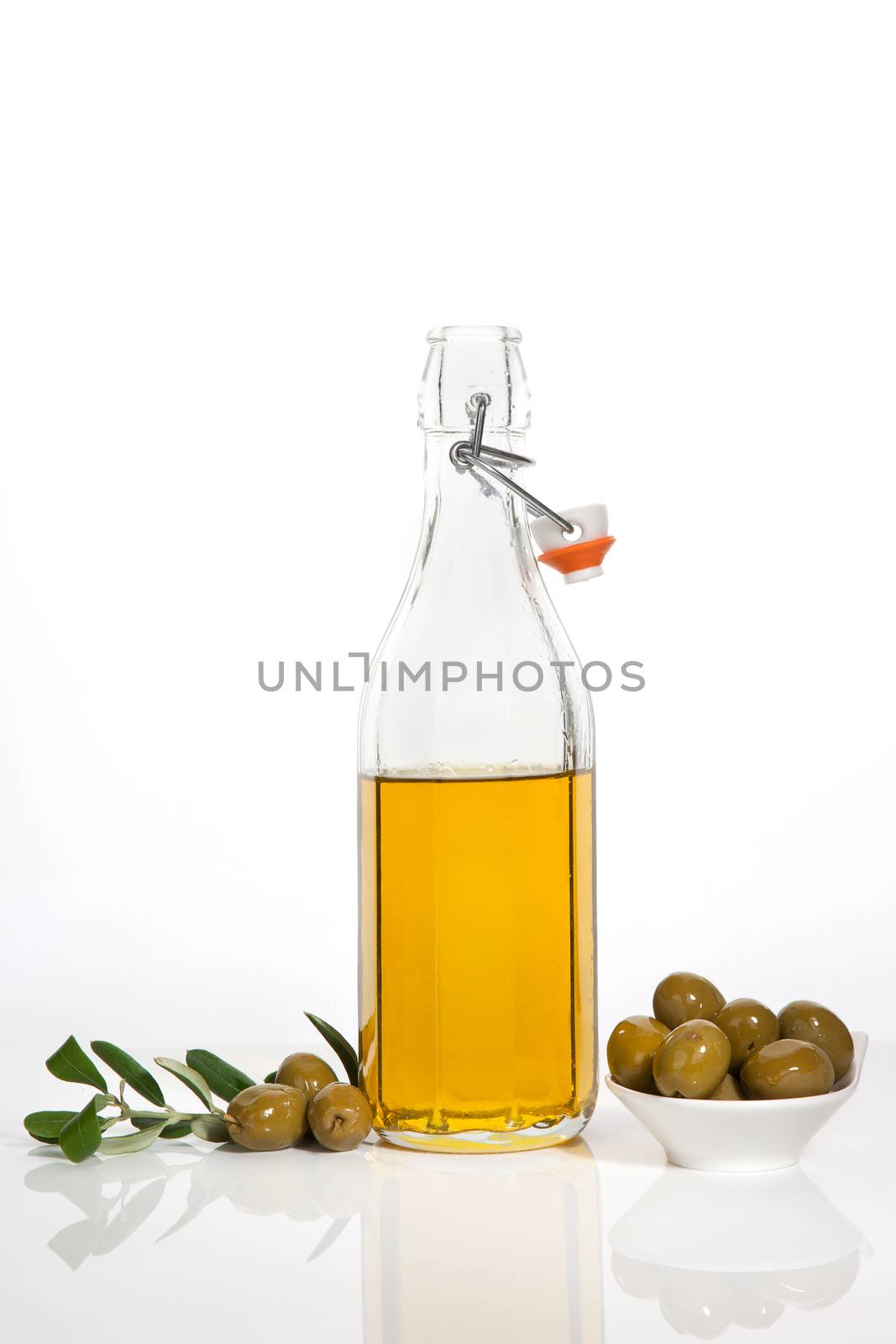 Olive oil in glass bottle, olives in bowl and fresh olive branch and leaves isolated on white background. Culinary cooking.