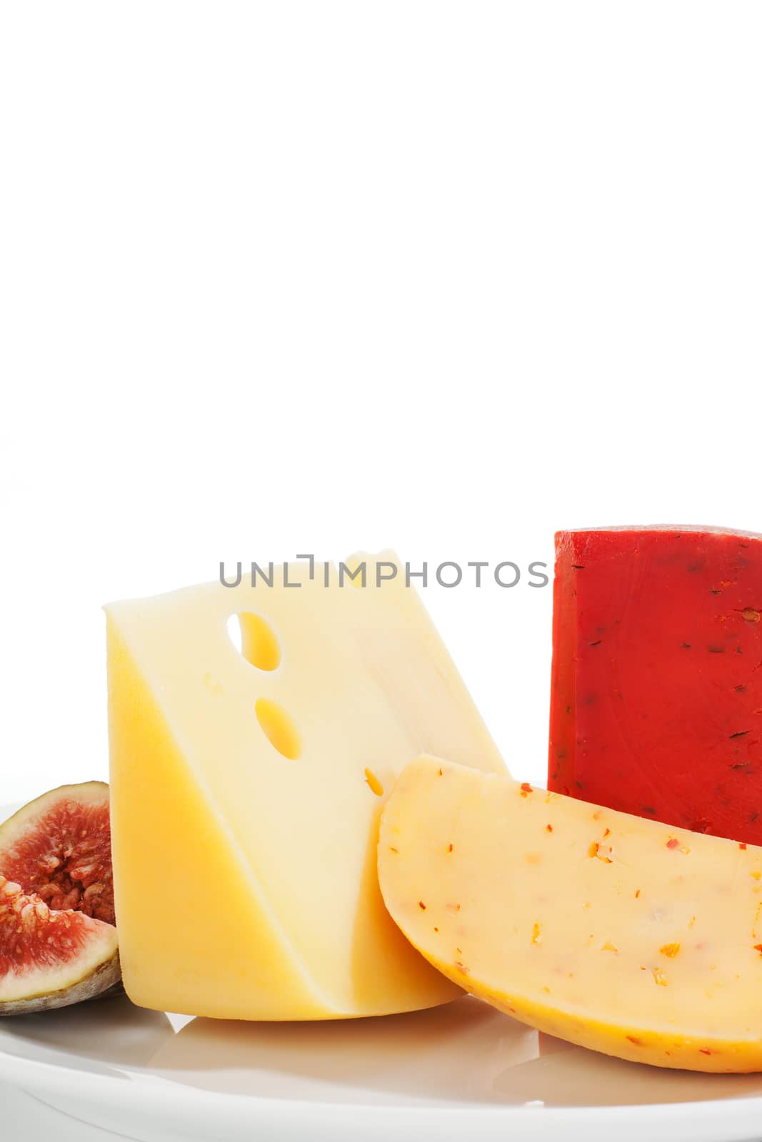 Colorful luxurious cheese background. Swiss cheese, gouda chlii and fig fruit on white plate isolated on white. Culinary eating background.
