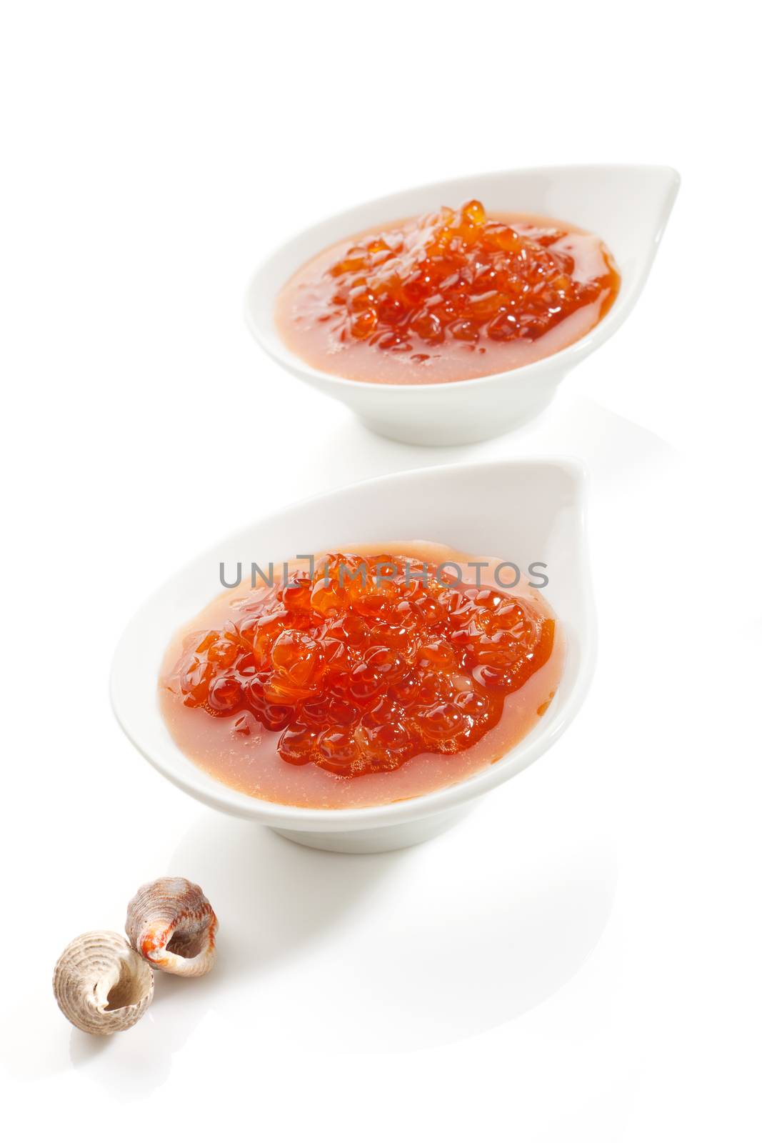 Two bowls with red caviar isolated on white background. Decorated with seashell, delicious luxury seafood concept.