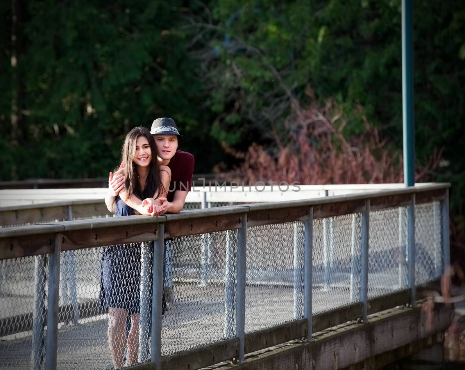 Happy young interracial couple standing on bridge over water