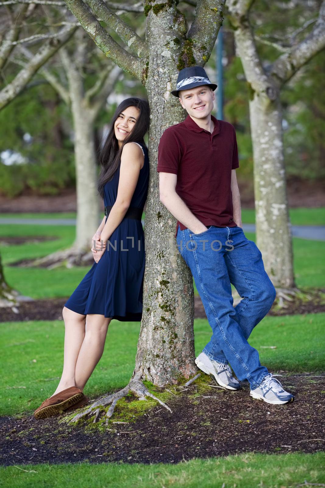 Young happy interracial couple standing together  by tree