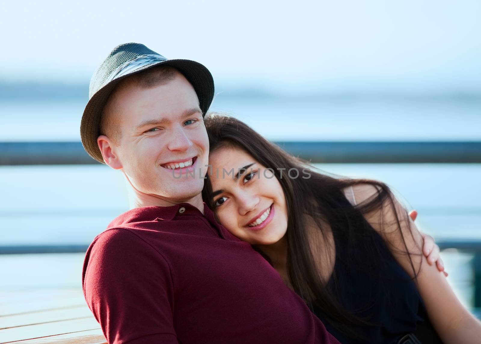 Young interracial couple in love, hugging outdoors by lake