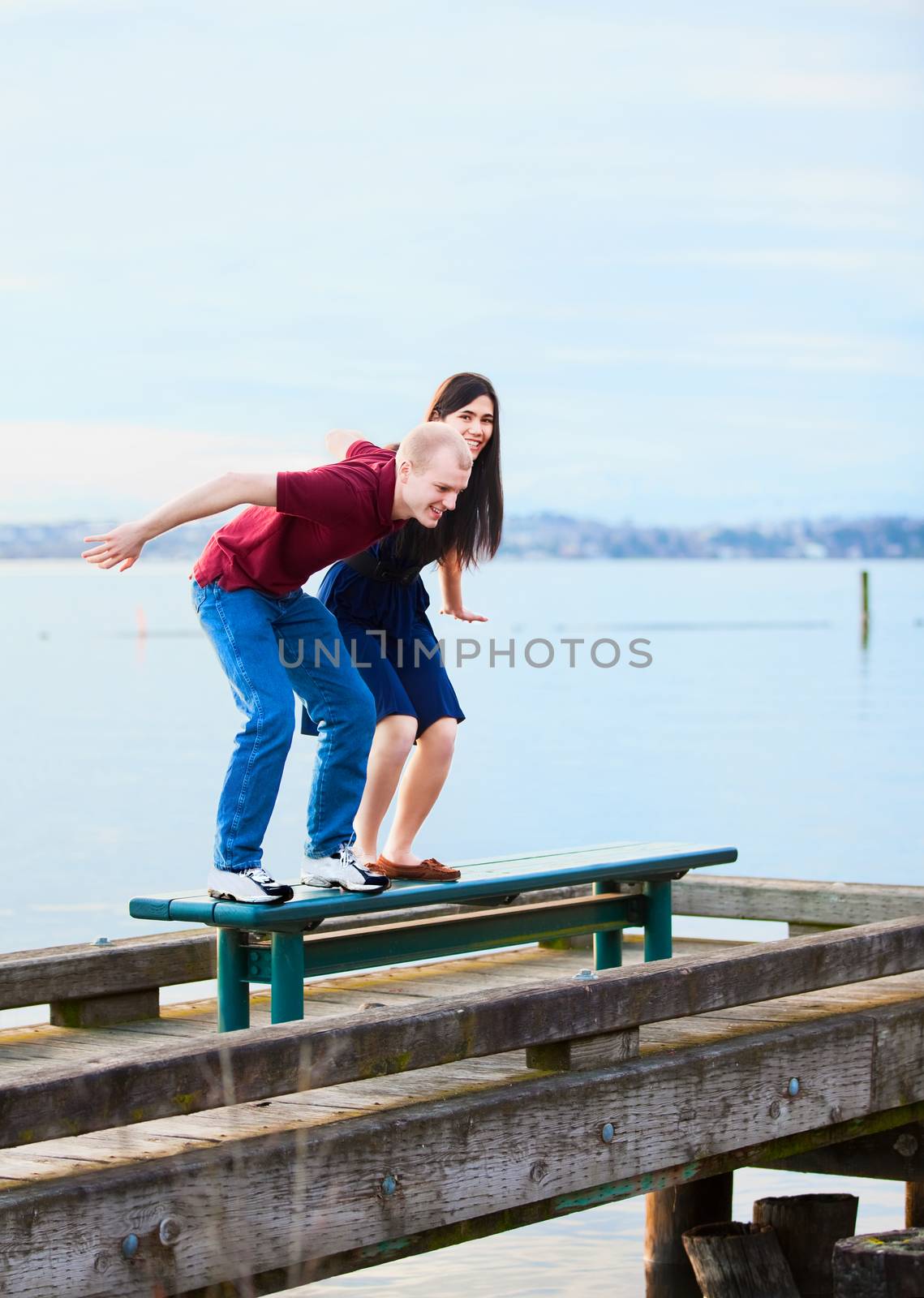 Happy young interracial couple  preparing to jump off  dock over lake, playful