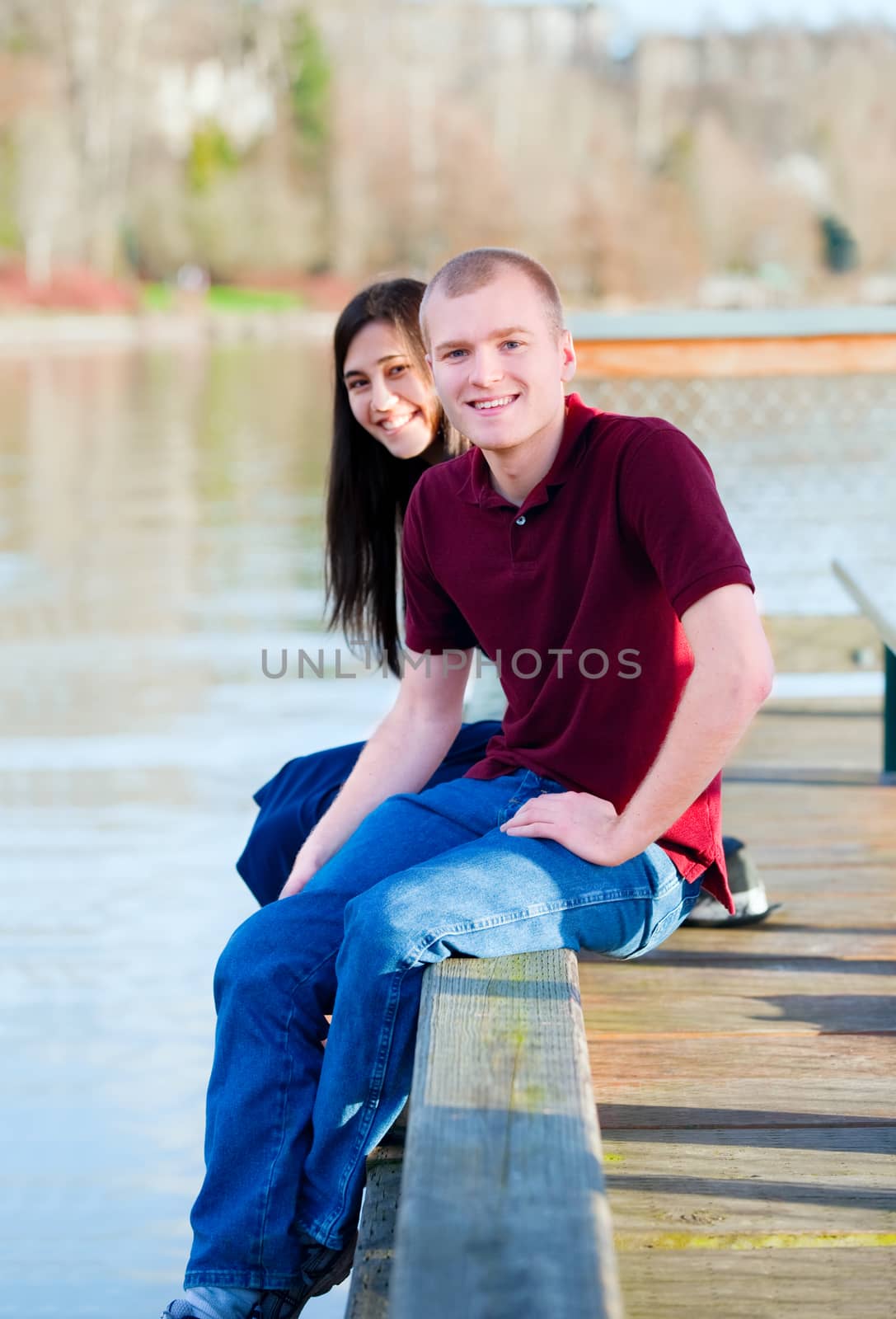 Beautiful interracial couple sitting on wooden dock over lake by jarenwicklund