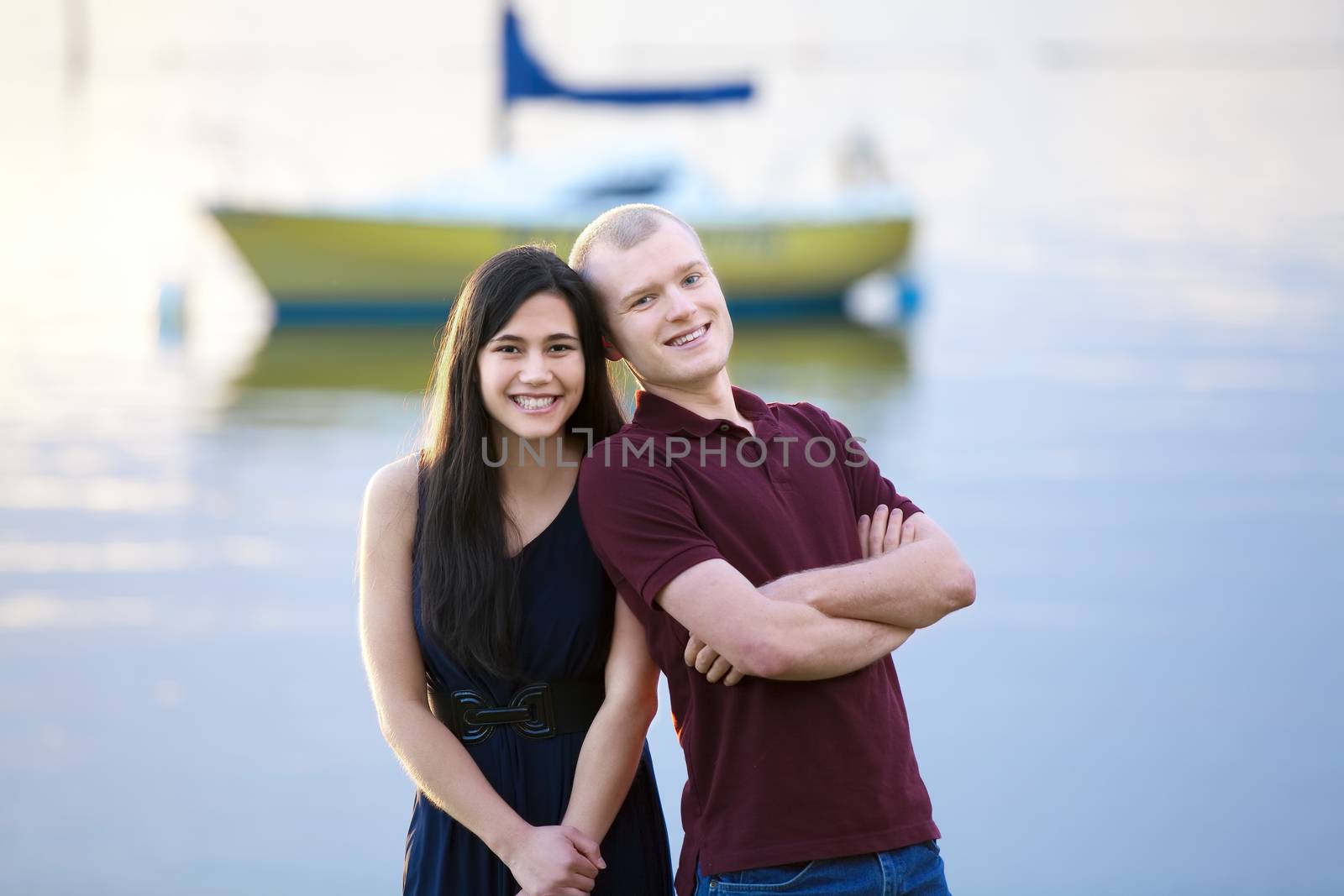 Happy young interracial couple standing together by lake by jarenwicklund