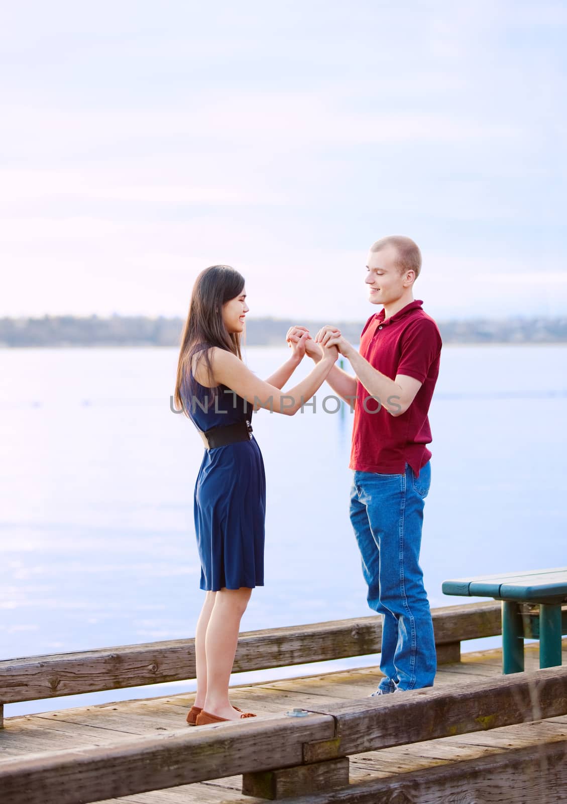 Young interracial couple holding hands standing on dock over lak by jarenwicklund