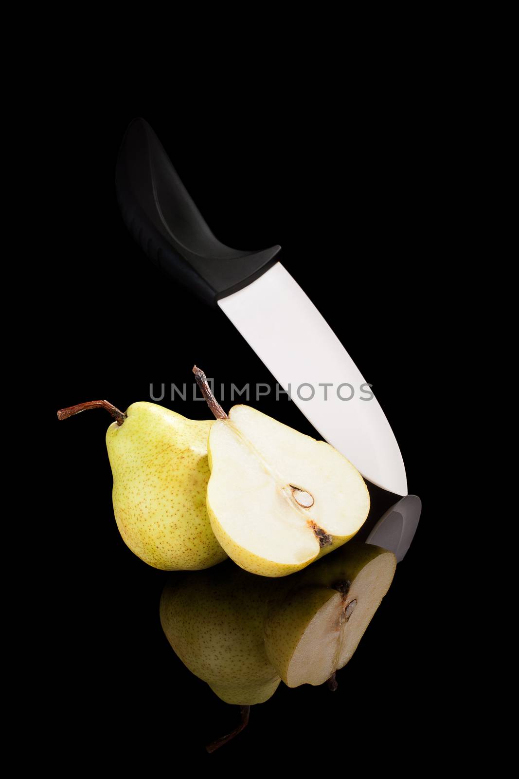 Pear with ceramic knife isolated on black background with reflection. Fruits in luxurious black.