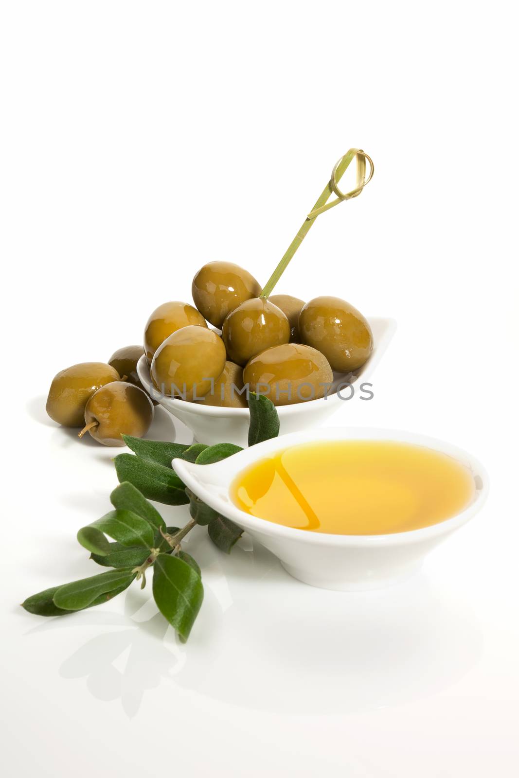 Green olives and extra virgin oliver oil with olive twig isolated on white background. Traditional olive background.