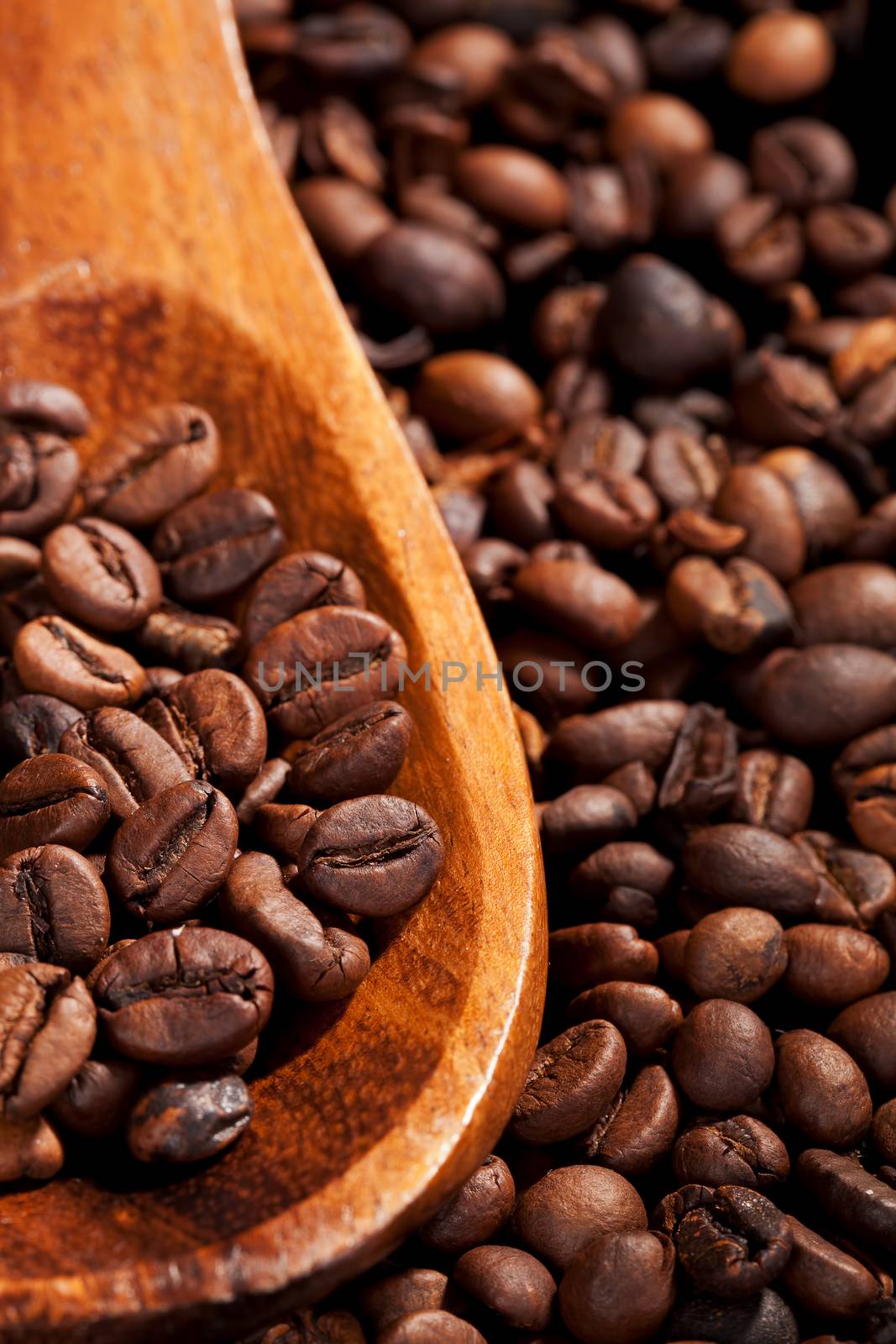 Coffee beans on wooden spoon on coffee beans background. Coffee still life.