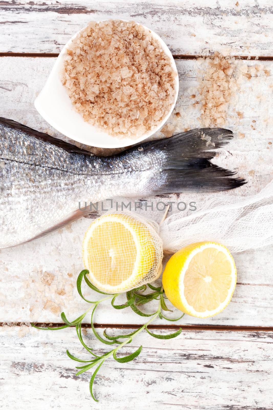 Fish tail with lemon, sea salt, fresh lemon on white wooden textured background. Culinary seafood background in white.