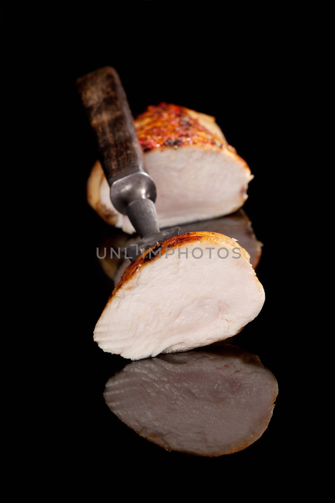 Delicious juicy chicken piece on fork, chicken steak in background isolated on black. Luxurious culinary eating.