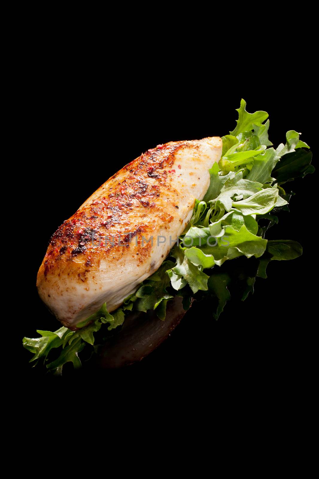 Delicious juicy grilled chicken breast with fresh salad isolated on black background. Luxurious culinary chicken meat concept.