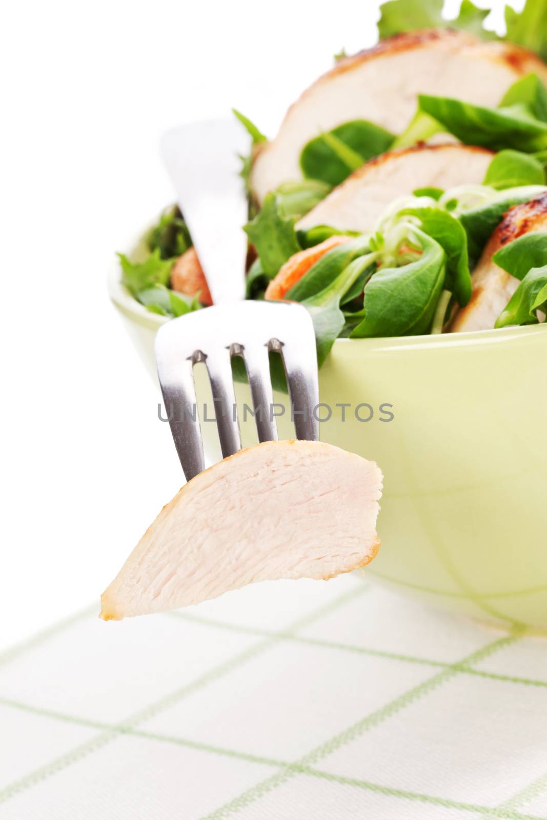 Fresh caesar salad with lettuce, carrot and chicken in bowl, chicken piece on silver fork. Luxurious light summer eating.