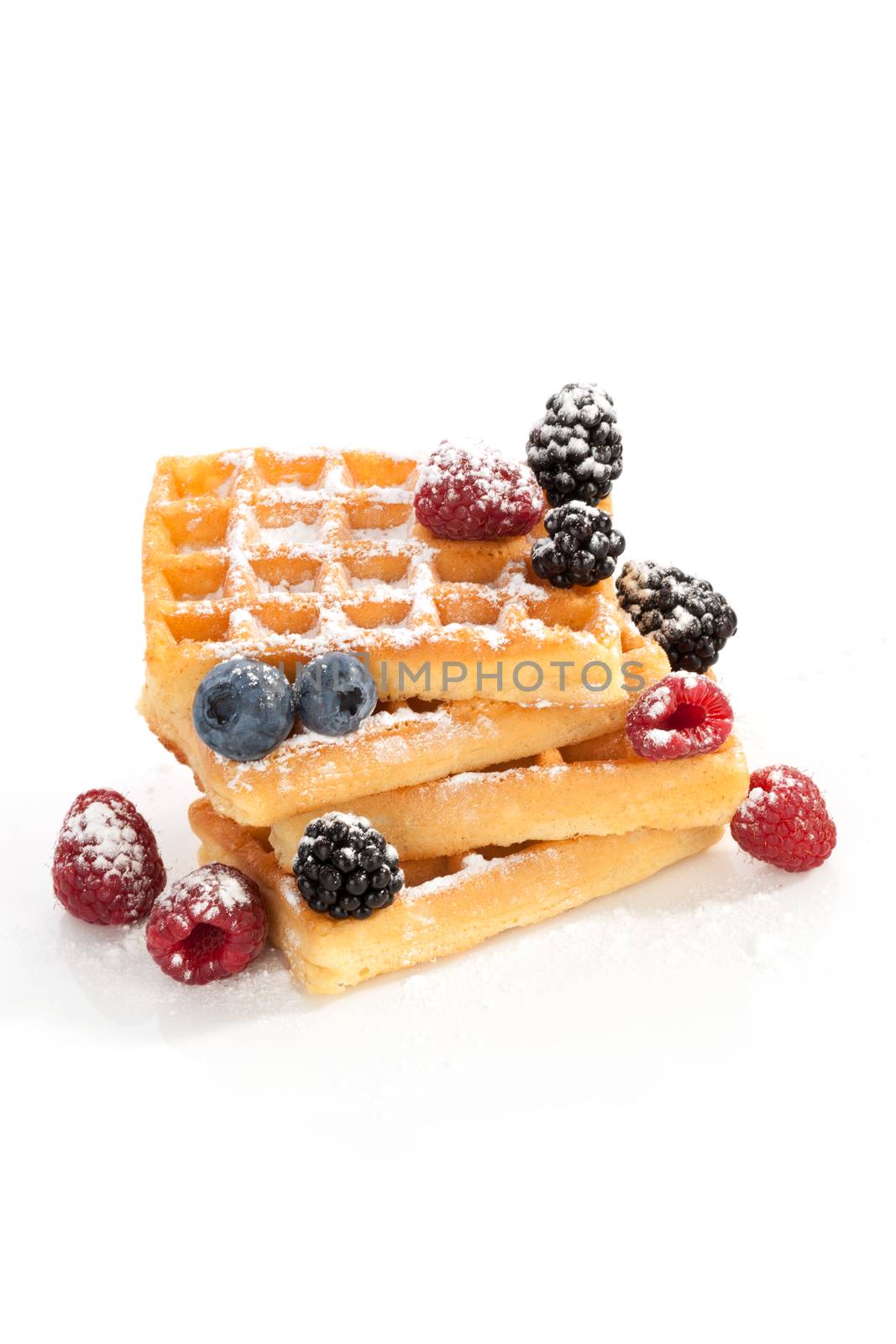 Waffle pile with raspberries, blueberries and blackberries isolated on white background. Culinary sweet dessert.