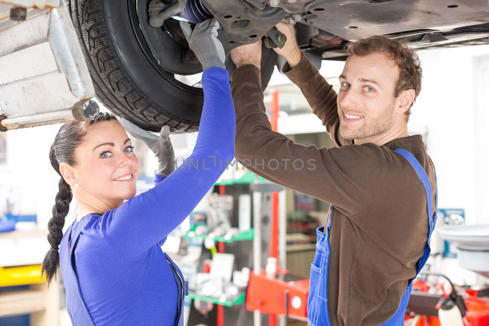 Two mechanics repairing or inspecting a car on hydraulic lift