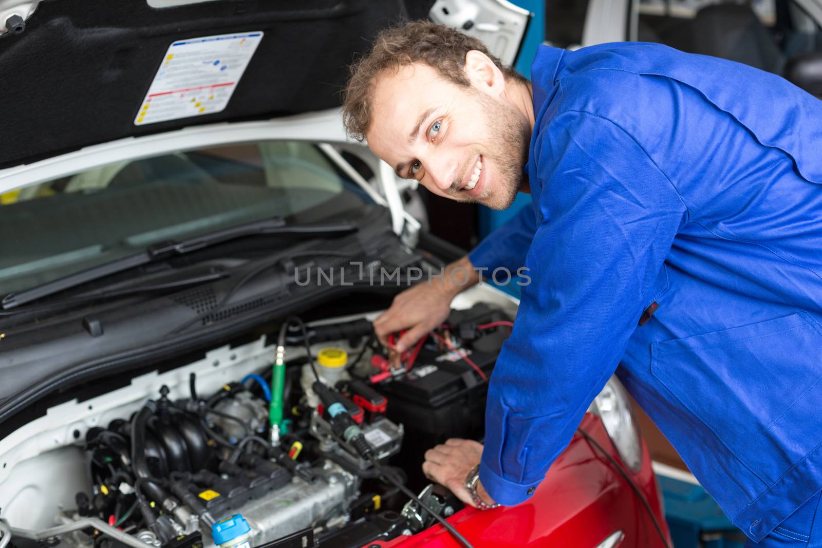 Mechanic repairing a car in a workshop or garage by ikonoklast_fotografie