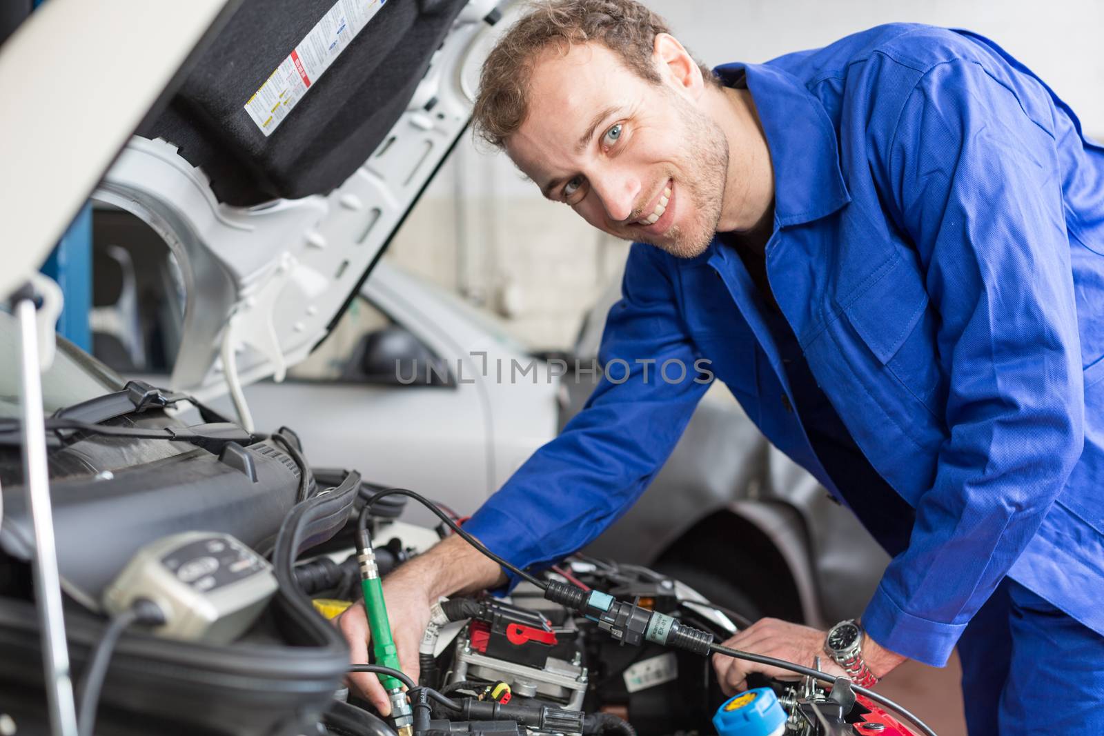 Mechanic repairing a car in a workshop or garage by ikonoklast_fotografie
